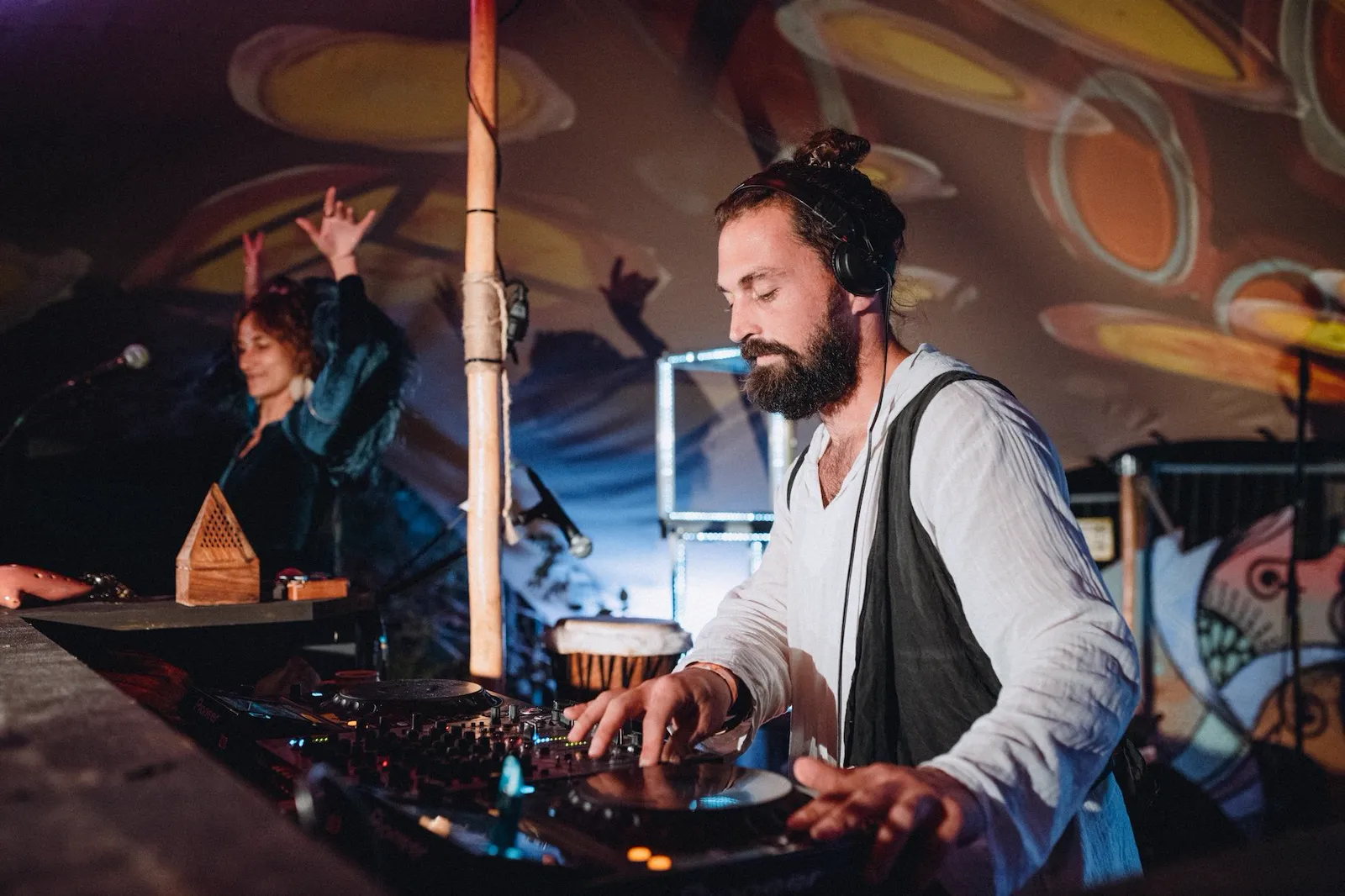 Oskabya at the decks, a dancer moves behind him
