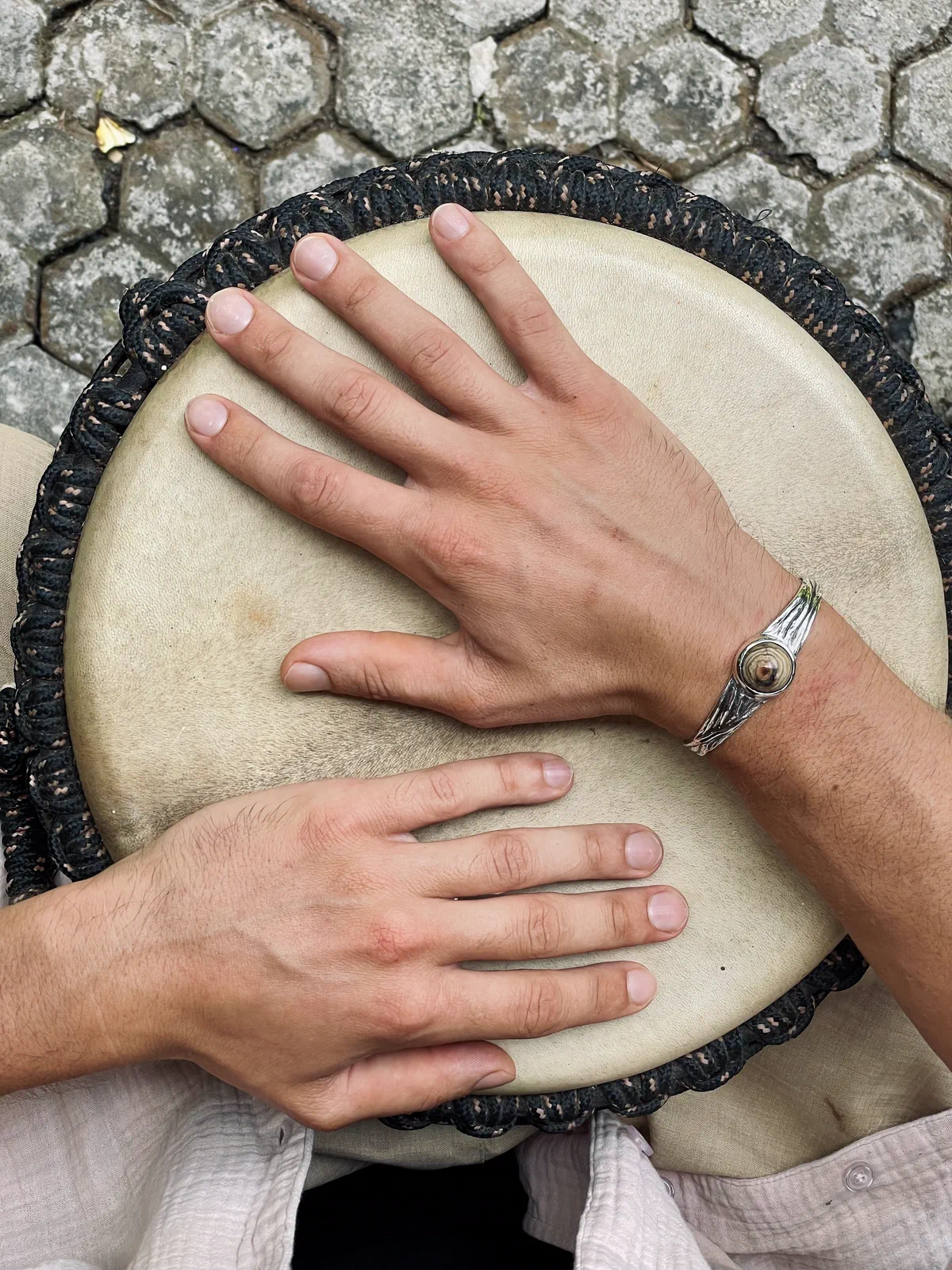 Hands on a djembe, with an MGK bracelet