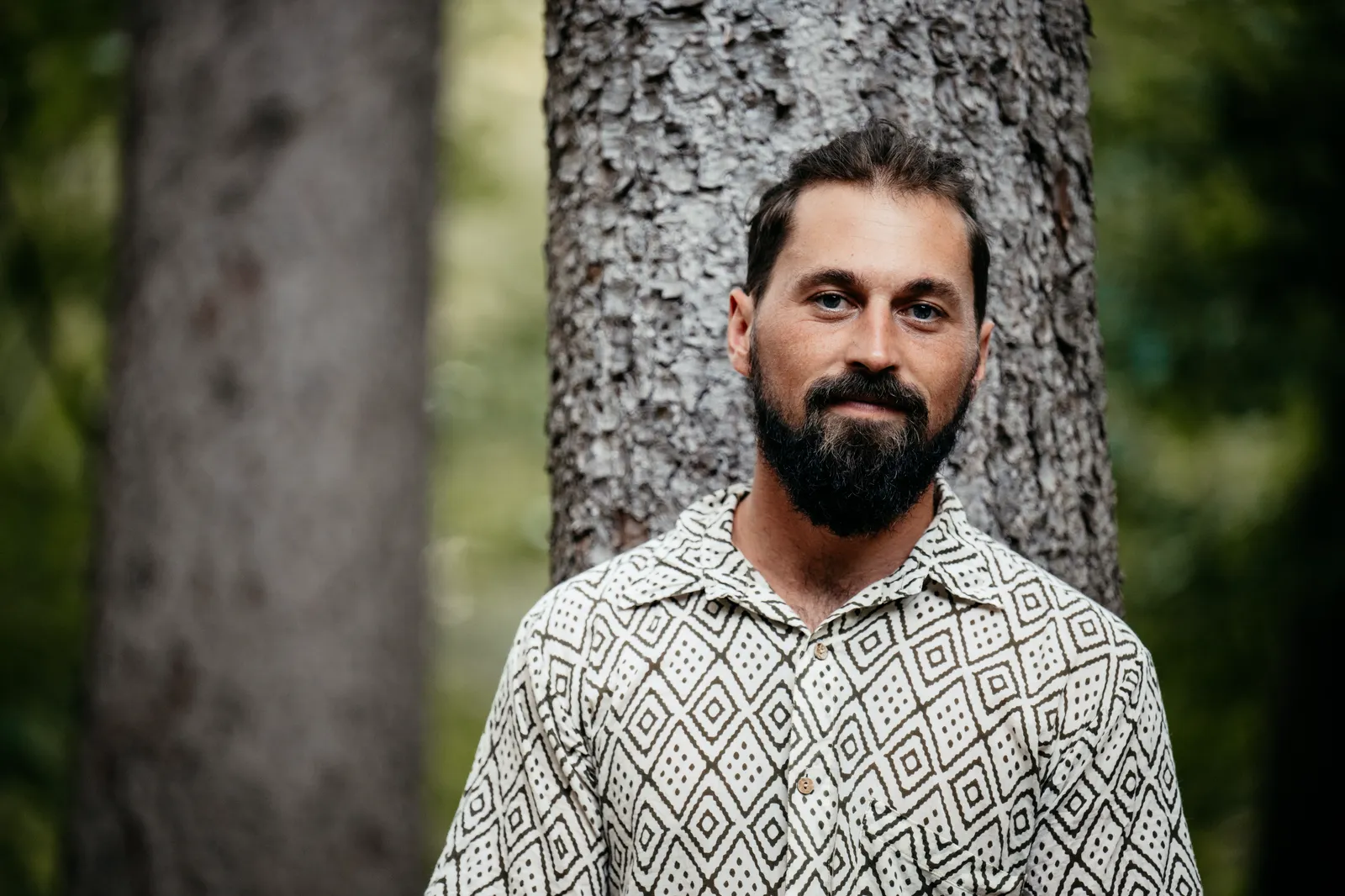 Simon Erdmann in front of a tree trunk in the forest